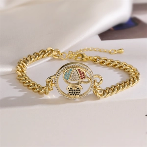 Close-up of gold curb chain bracelet with zircon-inlaid cartoon character pendant
