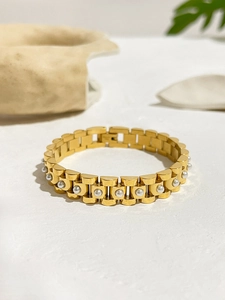 Detailed close-up of 18K gold watch band style bracelet with white pearl inlays