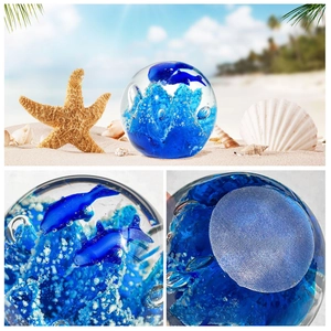 Macro detail of a crystal glass sphere with a blue dolphin and ocean floor textures