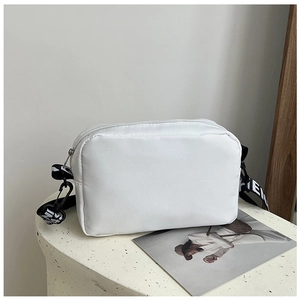 Detail of adjustable nylon wide strap with geometric patterns and letters on white bag