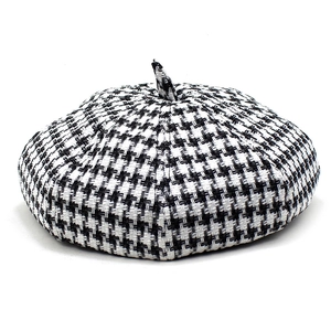 Top view of classic black and white houndstooth beret with a decorative top knot
