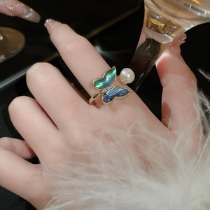 Detail of gold butterfly ring with colorful abalone wings and white pearl on finger