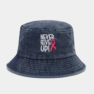 Détail de la broderie ruban rose et du texte Never Give Up sur le bob en jean bleu délavé