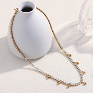 Detailed view of 18K gold-plated beaded necklace with cubic zirconia drapes over a vase