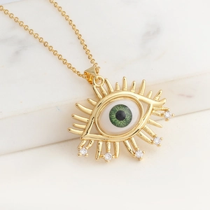 Detailaufnahme des goldenen Evil-Eye-Anhängers mit grüner Iris und Zirkon-Akzenten