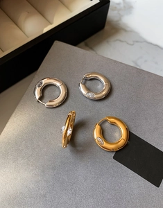 Detailed view of gold and silver hoop earrings with marquise-cut zircon insets