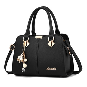 Close-up of black leather texture with gold hardware and a delicate flower pendant