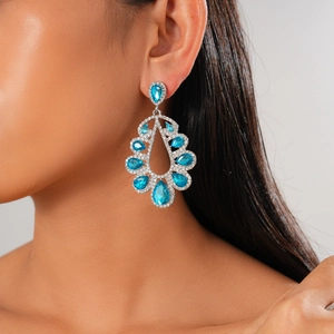 Close-up of luxury water-drop earrings with blue gems and diamonds worn by a model