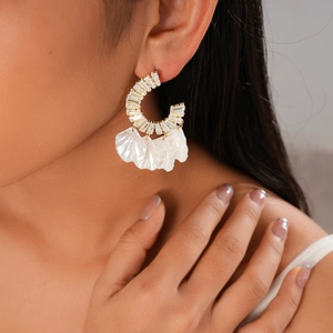 Vue détaillée de boucles d'oreilles créoles dorées en C avec zircons et glands nacrés