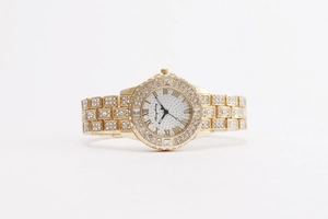 Gros plan d'une montre dorée avec lunette sertie de diamants et chiffres romains