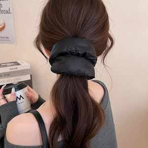 Macro detail of a high-quality black oversized puffy scrunchie worn on hair