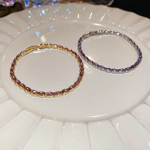 Detailed view of gold and silver tennis bracelets with purple oval-shaped gemstones
