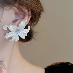 Detailed view of a pearlescent white lily stud earring with a central zircon accent