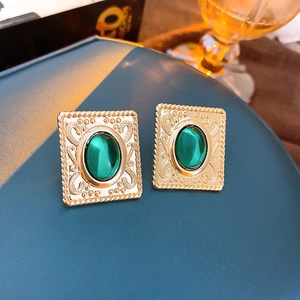 Detail of vintage gold square earrings with green oval gemstone and embossed patterns