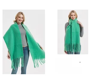 Detail of soft mohair-style thick green scarf showing tassel design and knit texture