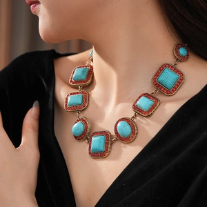 Nahaufnahme einer Vintage-Goldkette mit türkisen Steinen und roten Kristallen an einem Model