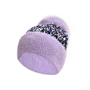 Detailed view of purple knit winter hat featuring sequin band and fluffy faux fur pompom