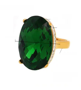 Makroaufnahme: Vintage-Ring mit grünem Glasstein und Kristallen auf vergoldetem Titan