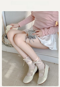 Close-up of pink ribbed socks with white lace trim and satin bow on Mary Jane shoes