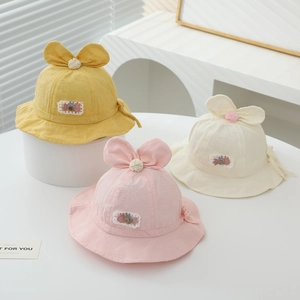 Detailed view of baby sun hats in yellow, pink and beige with rabbit ears and bows