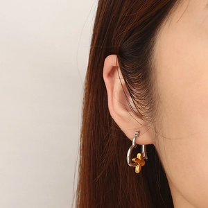 Elegant heart-shaped silver earrings with gold flower charms worn on a woman's ear