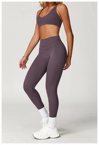 Detail of high-waisted yoga leggings and V-neck sports bra in deep purple fabric