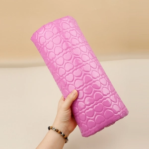 Detailed view of pink heart-quilted PU leather manicure arm rest with glossy finish