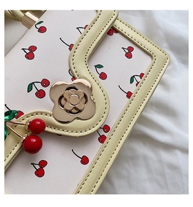 Detail of cherry pattern leather bag with flower clasp and cherry pendant