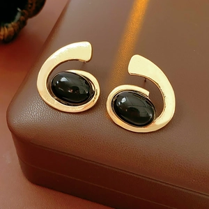 Vintage gold swirl stud earrings with oval black onyx stones on brown leather jewelry box