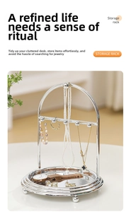 Detail of silver jewelry stand with arched rack, hooks and round mirrored base tray