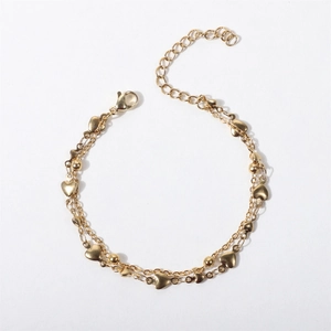 Detailed view of golden double-layer chain bracelet with heart charms and beads