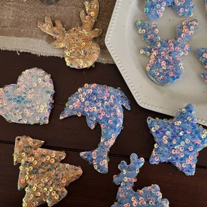 Sparkly sequin Christmas tree ornaments in blue and champagne on a rustic table