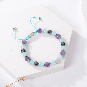 Detailed view of handmade beaded bracelet with heart charm on a decorative stone tray