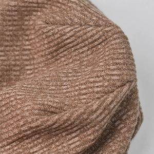 Close-up detail of the brown waffle knit texture and soft yarn fabric of the beanie hat
