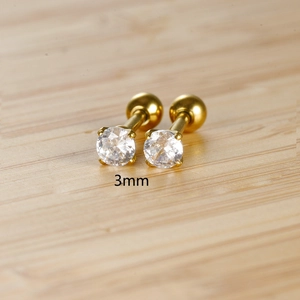 Macro shot of 3mm zircon gold studs with four-prong setting and screw-back on wood