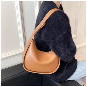 Vue latérale du sac porté épaule demi-lune en cuir camel porté par un mannequin élégant