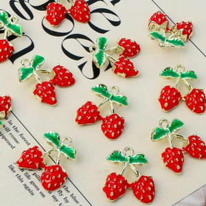 Macro view of 11 metal strawberry pendants with red enamel on vintage paper background