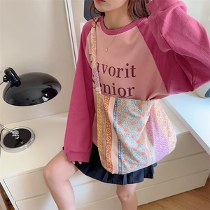 Close-up of canvas crossbody bag with floral patterns and pink raglan sleeve sweatshirt