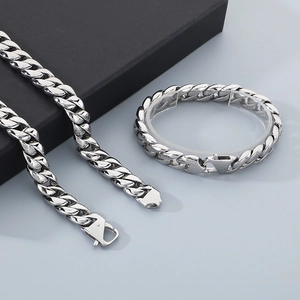 Detailed view of silver 12mm Cuban chain necklace and bracelet set on a display stand
