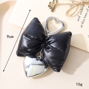 Detail of black faux leather bow charm with silver heart pendant and metal spring clasp
