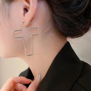 Gros plan de grandes boucles d'oreilles croix évidées en argent portées par un mannequin