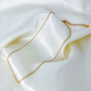 Close-up of minimalist gold titanium steel necklace on elegant white silk background