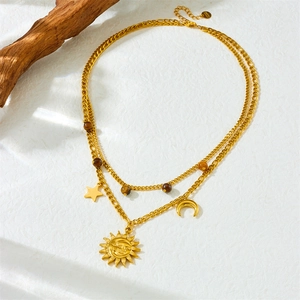 Double-layered gold necklace with sun, moon and star pendants on white textured fabric