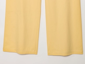 Vue détaillée des coutures et du tissu en sergé jaune du pantalon large élégant