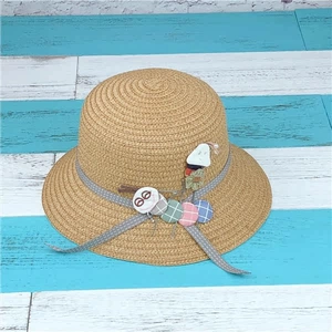 Close-up of children's straw sun hat with polka dot ribbon and cartoon caterpillar
