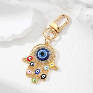 Macro shot of golden Hamsa Hand keychain with colorful evil eye charms and rhinestones