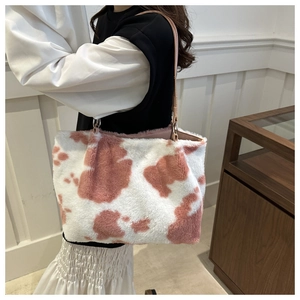 Detail view of pink and white cow print faux fur tote bag worn by a model in daily life