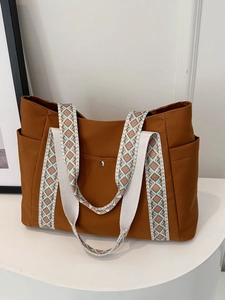 Dettaglio borsa tote in tela marrone con tracolla in tessuto a motivo geometrico