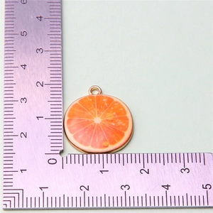 Detailed view of orange slice alloy pendant showing 2.5cm size with a ruler measure