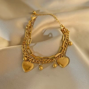Double-layer gold heart bracelet featuring cuban and paperclip chains on beige silk
